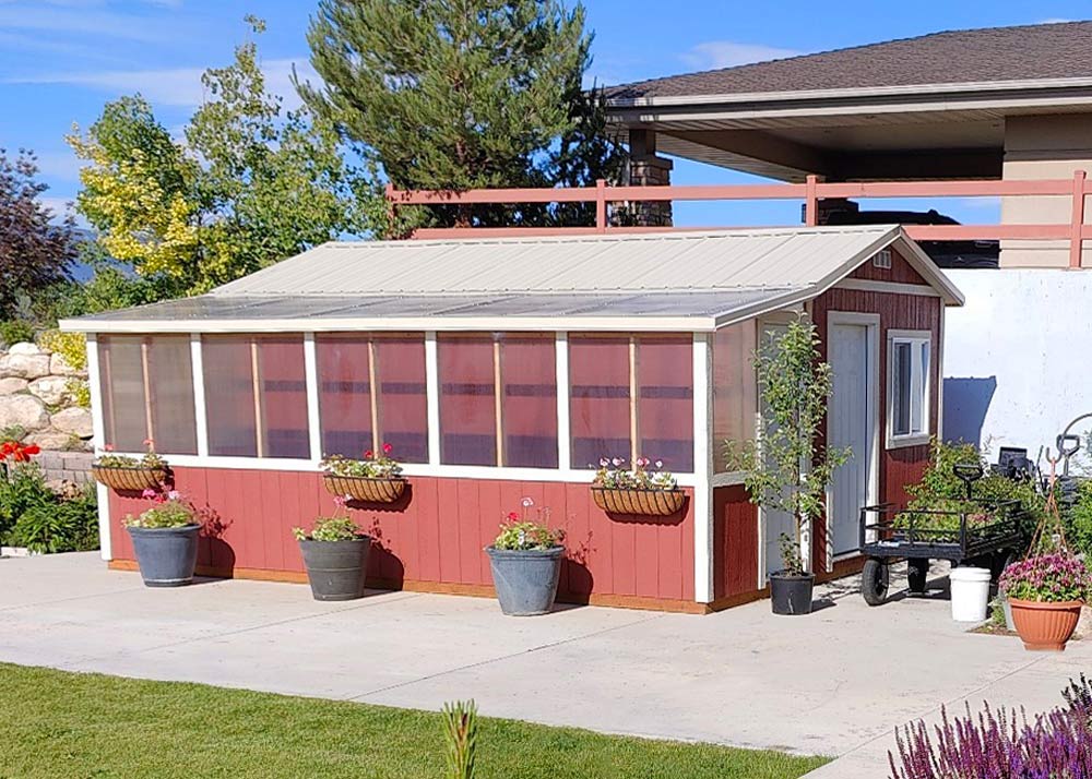 A custom shed and greenhouse combination in red with tan trim