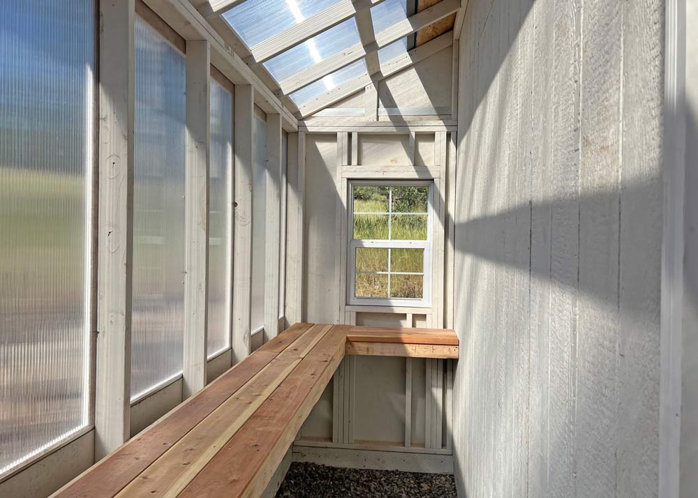 The interior of a lean-to greenhouse attached to a custom shed